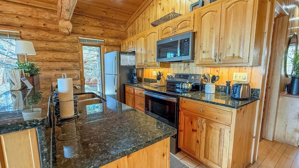 Step into your rustic cabin kitchen where granite countertops and warm wood create the perfect space for preparing mountain meals together.