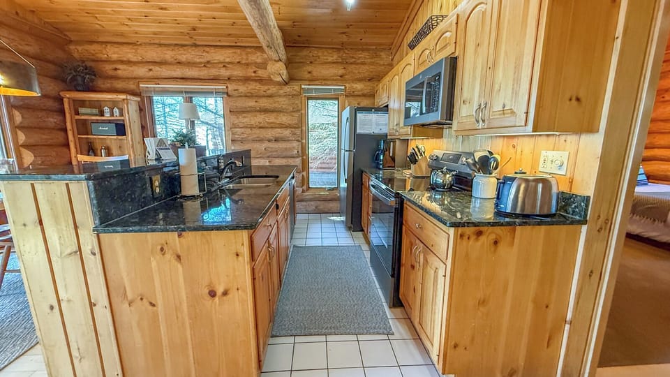 Your rustic log cabin kitchen features granite countertops and modern appliances for cozy meal prep.