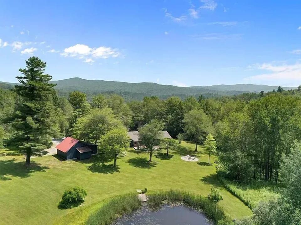 Sweeping aerial views of the property, private pond, and rolling mountain backdrop on beautifully ma