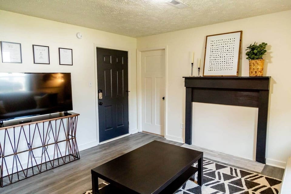 Sage Green Getaway - Living room space with view of the front door and the bedroom entrances.  Includes a cute little faux fireplace feature and smart TV, ready for you to log into your favorite personal streaming app subscriptions!