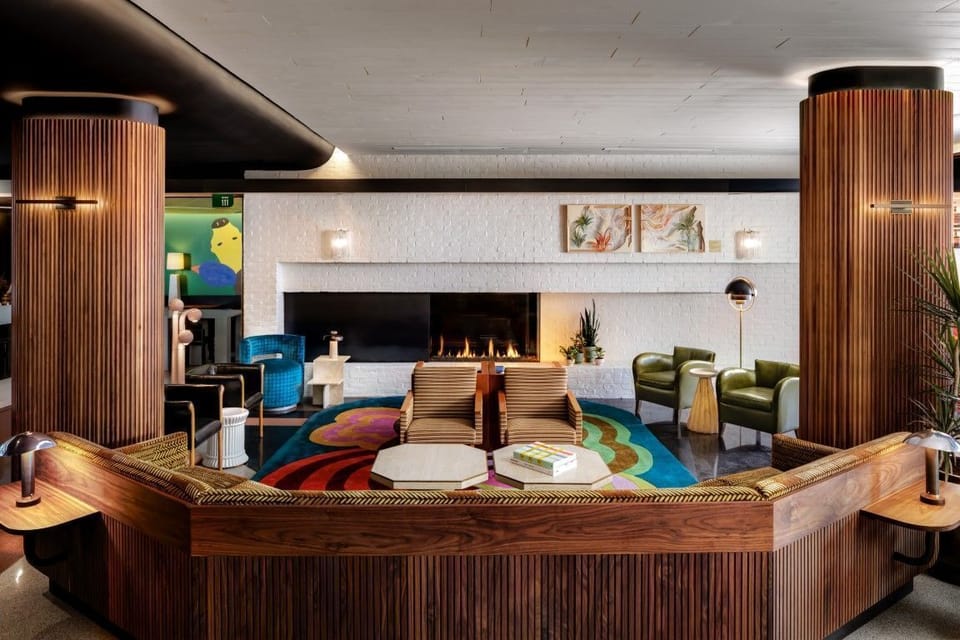 A cozy lounge area in The Drake Hotel highlights its art-forward design with a stunning fireplace, surrounded by bold colors and unique seating.