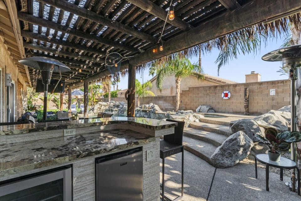 Covered outdoor kitchen w/ built-in grill, bar seating & shaded space for easy entertaining