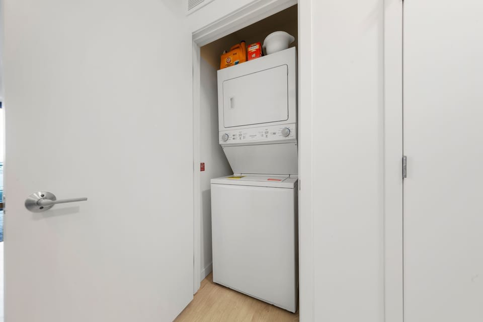 A clean and spacious laundry area with stacked washer and dryer units, making it easy to keep your clothes fresh and clean during your stay. The room is equipped with everything you need for a smooth laundry experience.