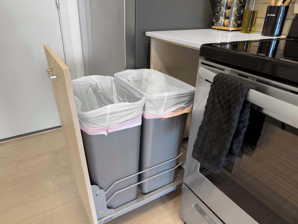 A neatly organized kitchen with convenient trash and recycling bins, ensuring a clean and efficient space. The modern design complements the functionality of this area, making cooking and clean-up easy during your stay.