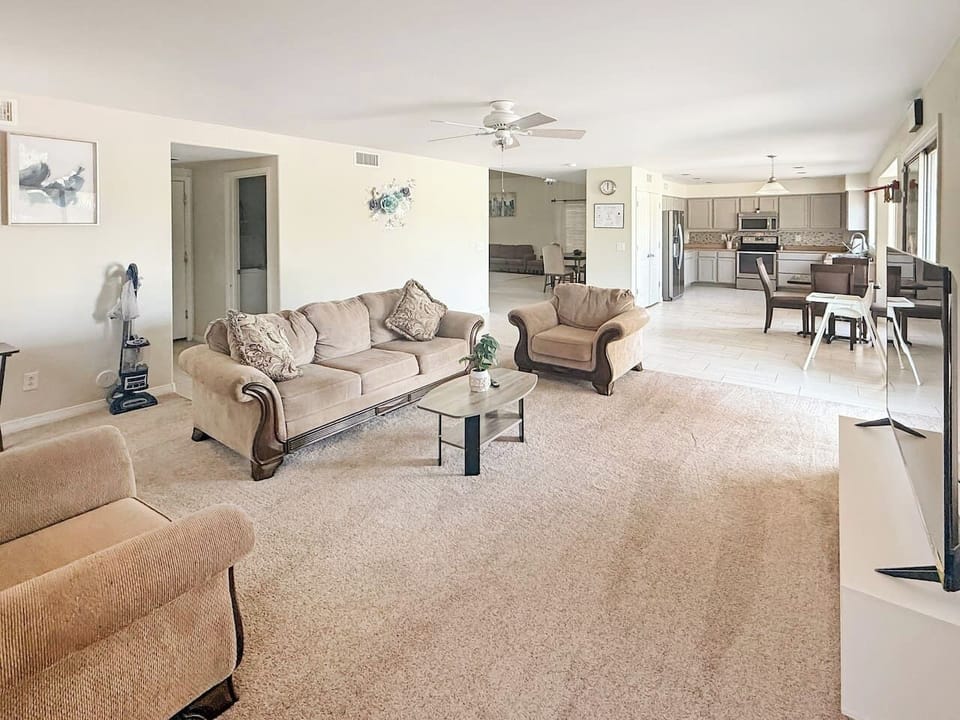 Large living room with sofas, coffee table, TV, and dining area beyond