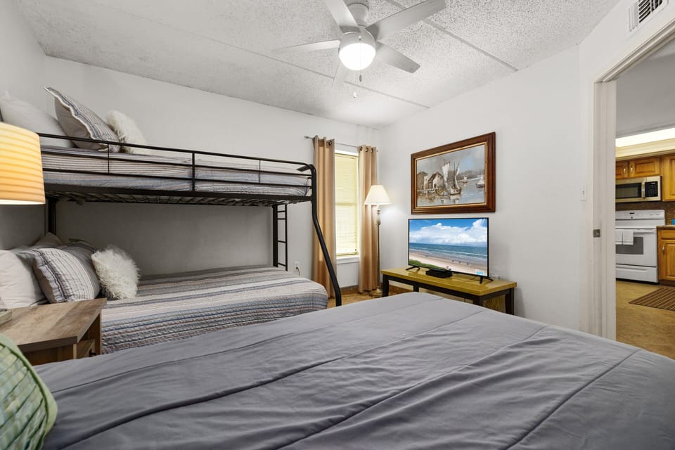 Guest bedroom with a twin bed, twin-over-full bunk and TV for relaxing after a day at the beach