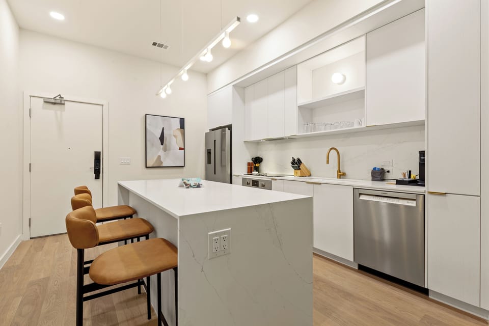 Cook, gather, and unwind in this bright modern kitchen featuring sleek finishes, stainless steel appliances, and island seating for the whole group.