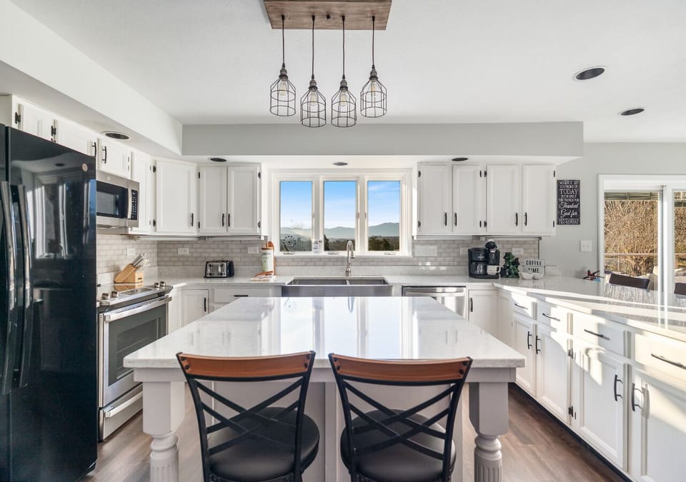 Full kitchen overview highlighting ample storage, island seating, and natural light.