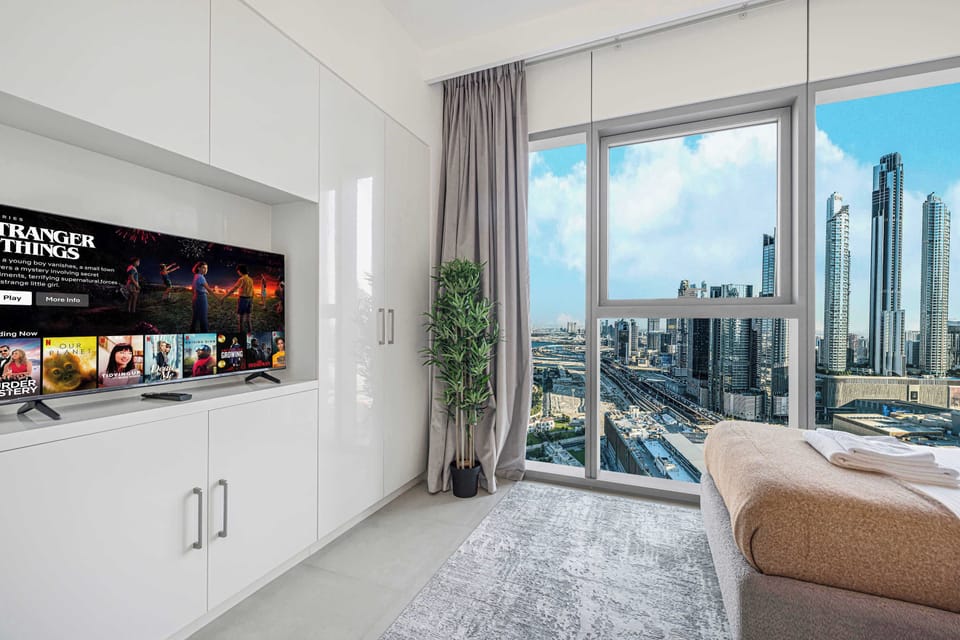 Bedroom with a TV and large window overlooking the city.