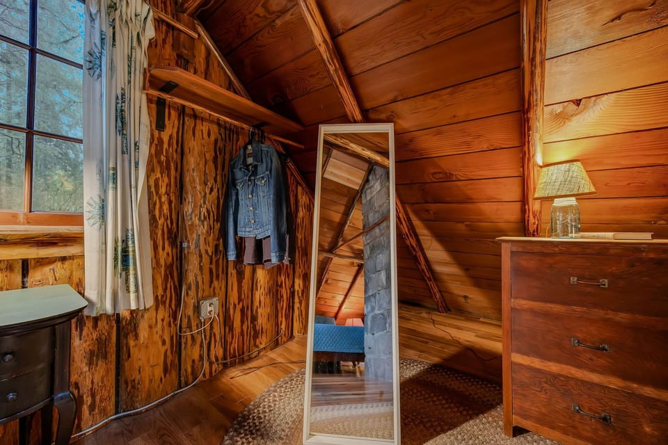 Your cozy wooden bedroom offers rustic charm with natural light streaming through windows and thoughtful storage solutions.