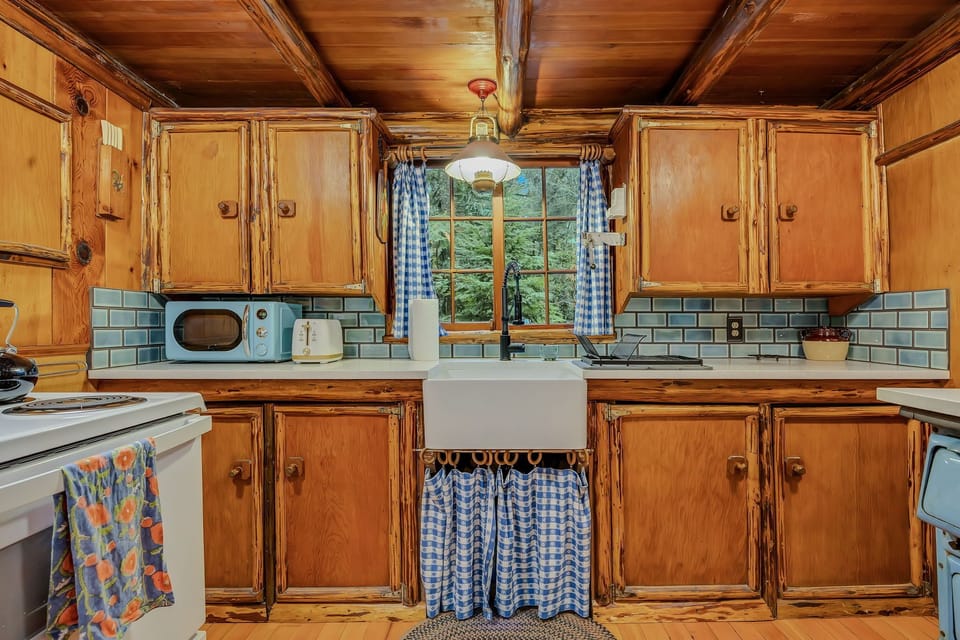 Rustic charm meets modern convenience in your fully equipped kitchen, where warm pine wood and cheerful blue accents create a cozy cooking haven.