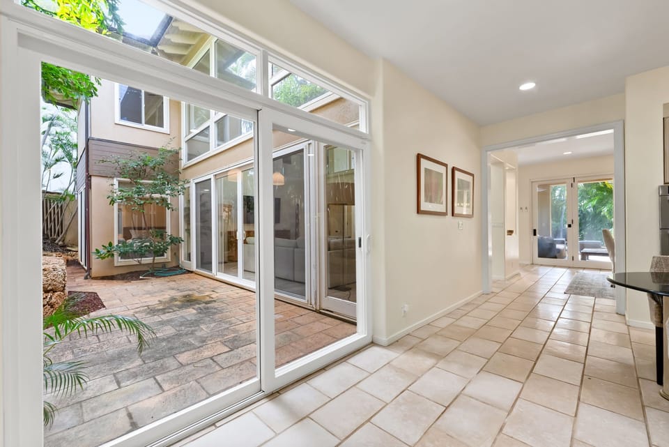 Step into your bright, open living space where floor-to-ceiling windows frame your private courtyard oasis.