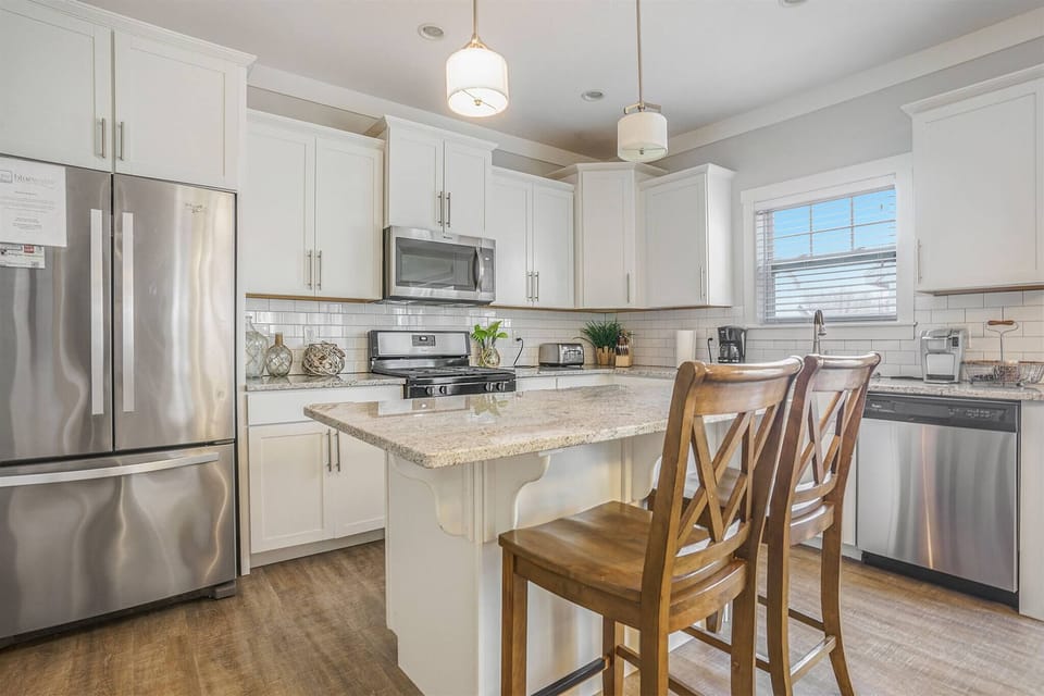 Stylish and functional kitchen offering stainless steel appliances, a roomy island with bar seating.