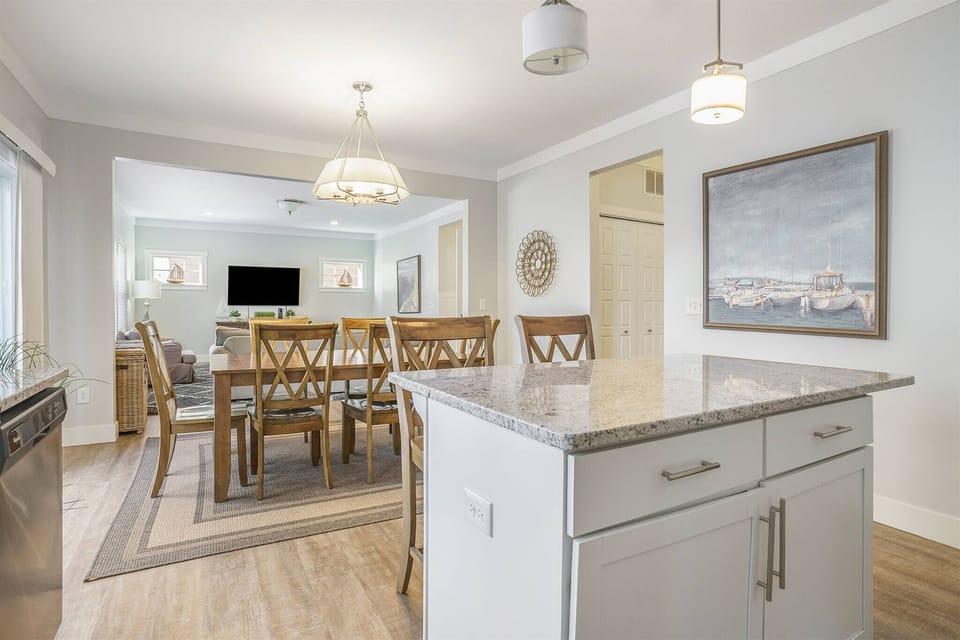 Bright and spacious kitchen and dining area featuring a large island, modern appliances, and a family-sized dining table. The open layout flows seamlessly into the living room, making it ear to cook, dine, and gather together