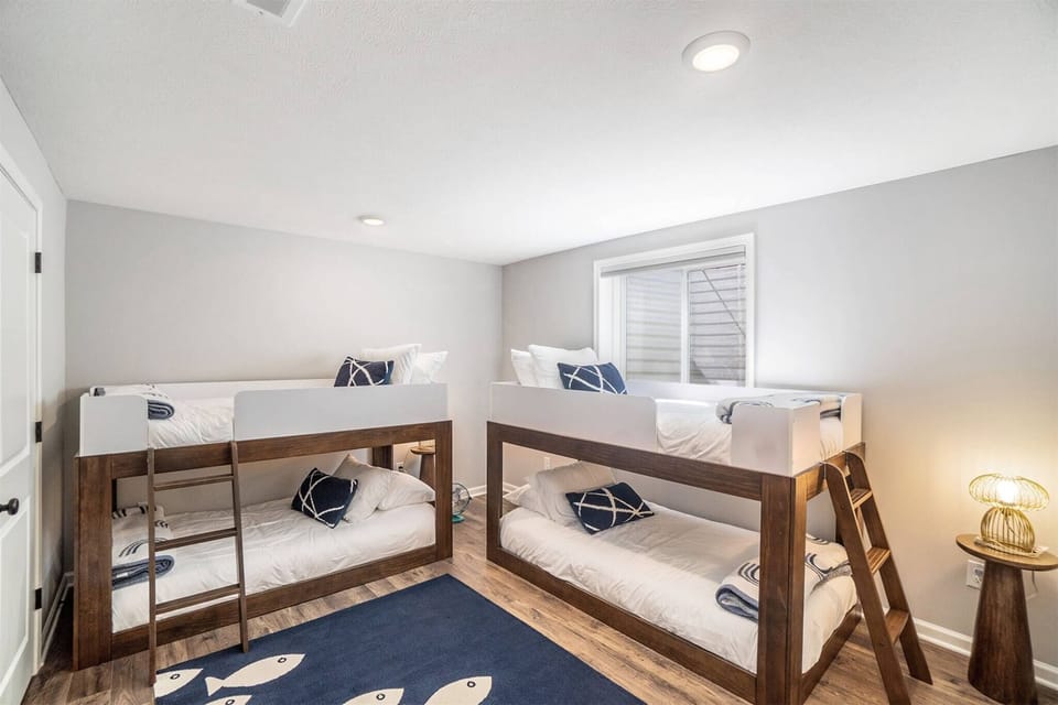 Spacious basement bunk room featuring two twin-over-twin bunk beds, cozy bedding, and plenty of room for kids or groups to relax.
