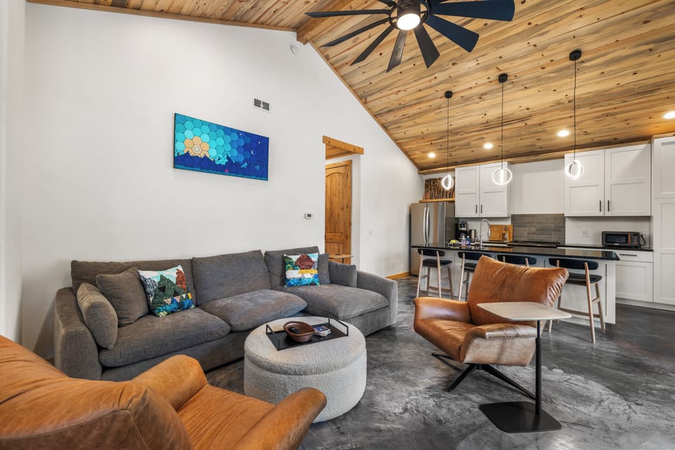 Open-Concept living, dining and kitchen space, with comfy couches and leather lounge chairs, centered around the Smart TV.