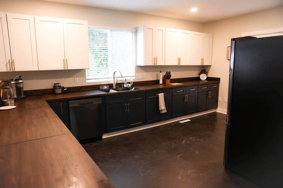 This charming kitchen is designed for both comfort and functionality. Featuring a sink, ample cabinet space, a refrigerator, and a stove, it has everything you need for cooking meals.