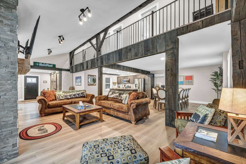 A spacious open-concept living area featuring cozy seating, rustic beams, and a warm, inviting atmosphere perfect for gathering and relaxing.