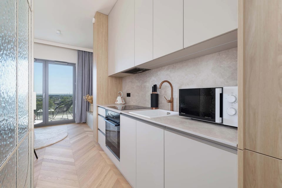 A sleek kitchenette featuring built-in appliances, minimalist white cabinetry, and a coffee maker on the counter.