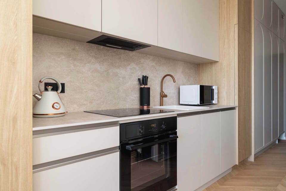 A warm-toned kitchen corner with under-cabinet lighting and light wood finishes enhancing functionality and style.