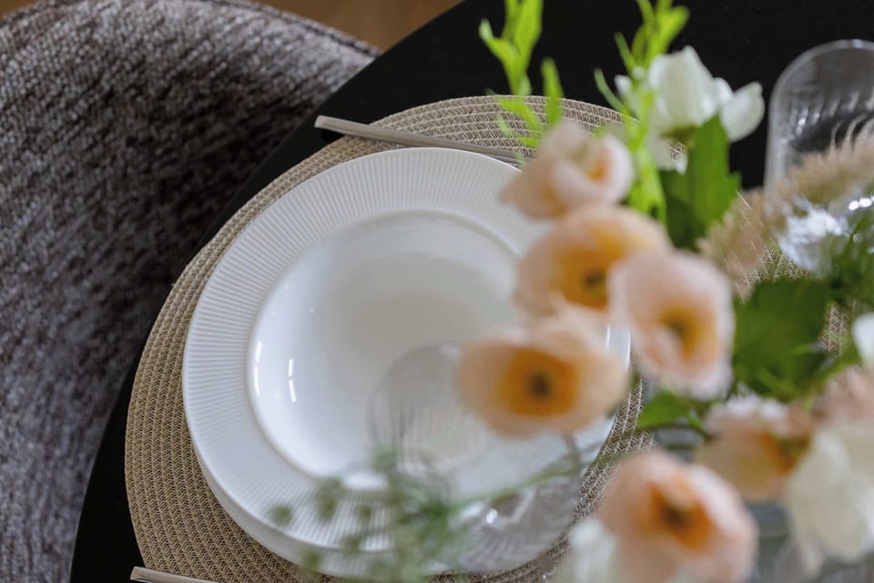 A beautifully set dining table with pastel flower arrangements and elegant dishes, perfect for an intimate meal.