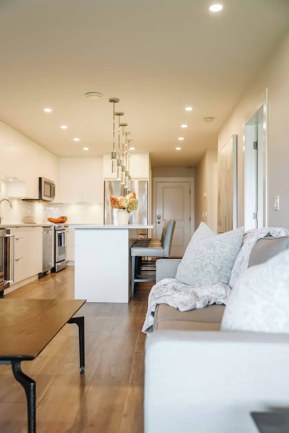 The living room features a cozy couch, coffee table, and chairs, while the kitchen with bar stools invites casual dining and conversation.