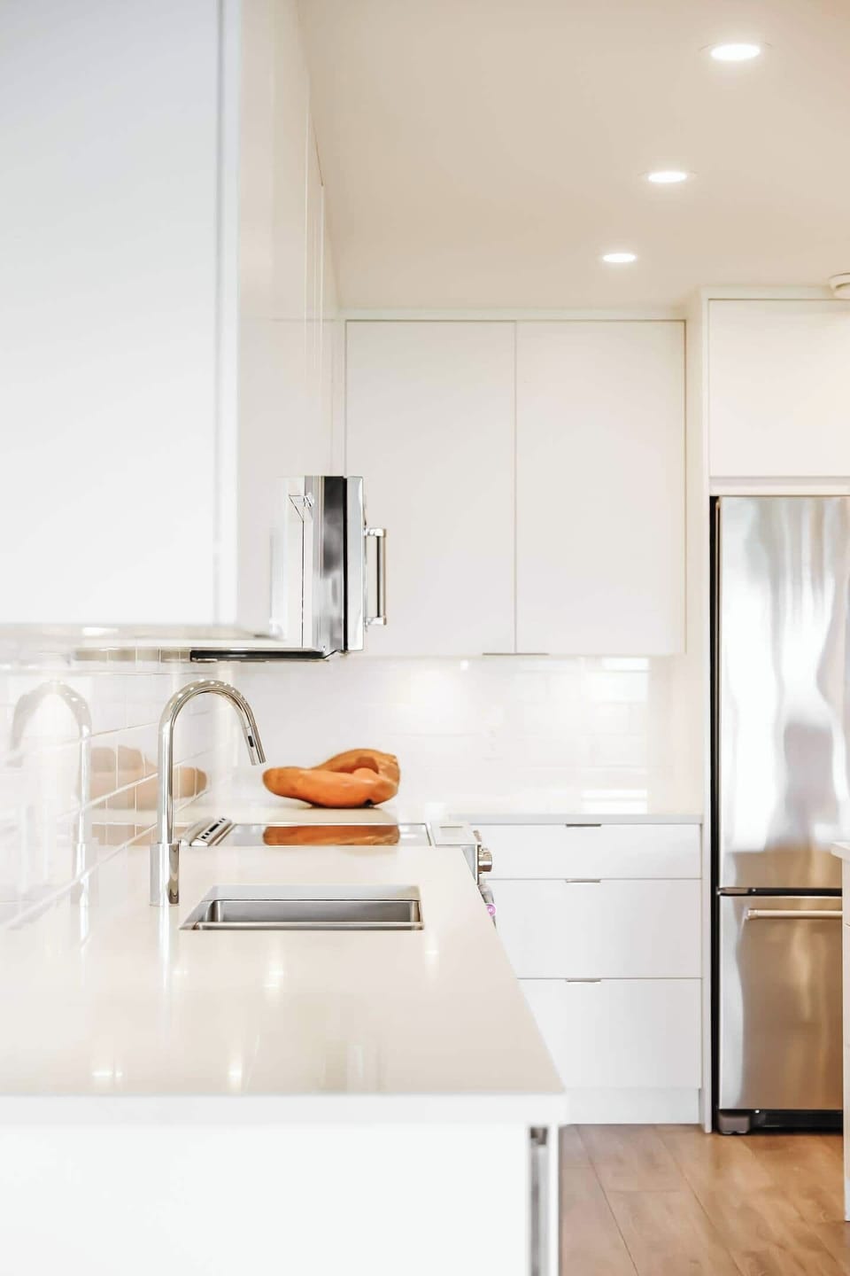 Modern kitchen with white cabinets, stainless steel appliances, spacious island, pendant lights, and plenty of natural light.