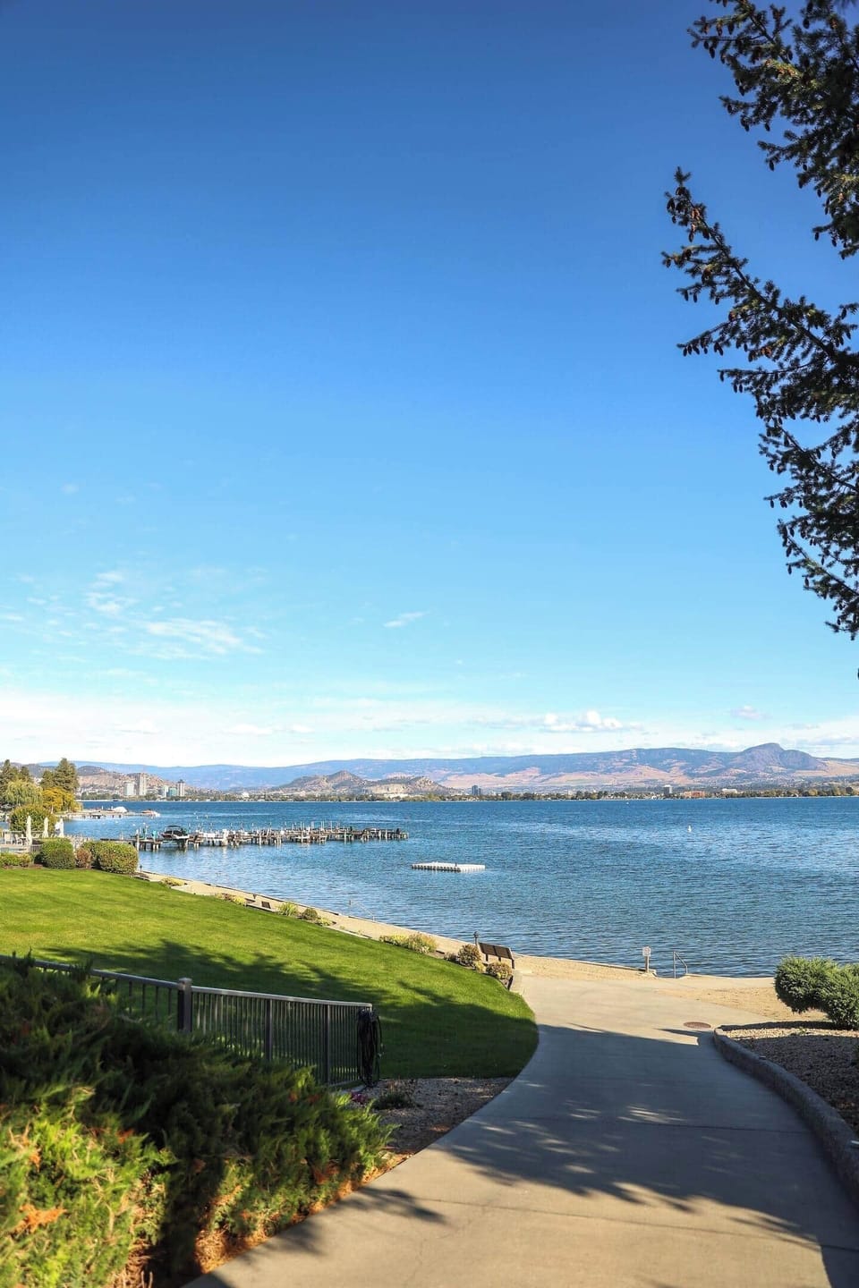 Sandy beach with a calm body of water and hills in the distance, offering a peaceful natural setting.
