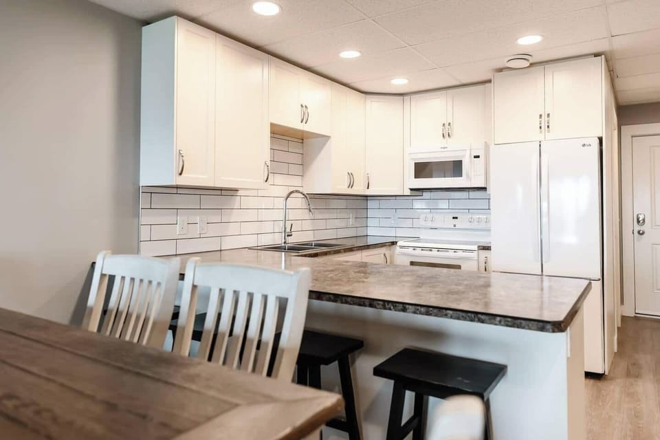 Kitchen island and dining area with white chairs and a wooden table, perfect for meals and gathering.