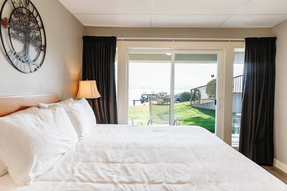 A bright bedroom with a large bed, and a glass door opening to the outdoors, inviting natural light.