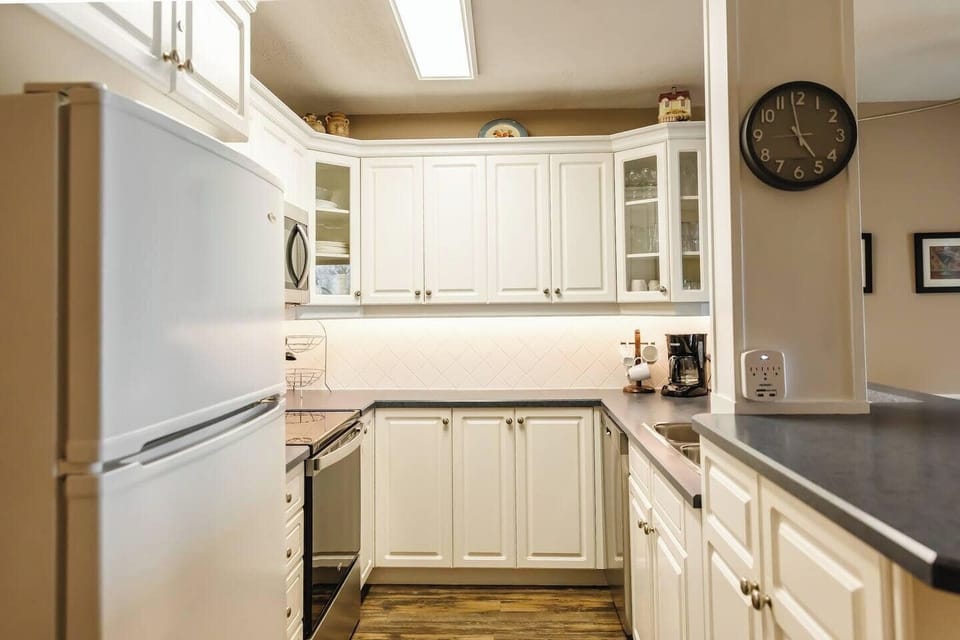 Modern kitchen with white cabinets, a stove, and a refrigerator.
