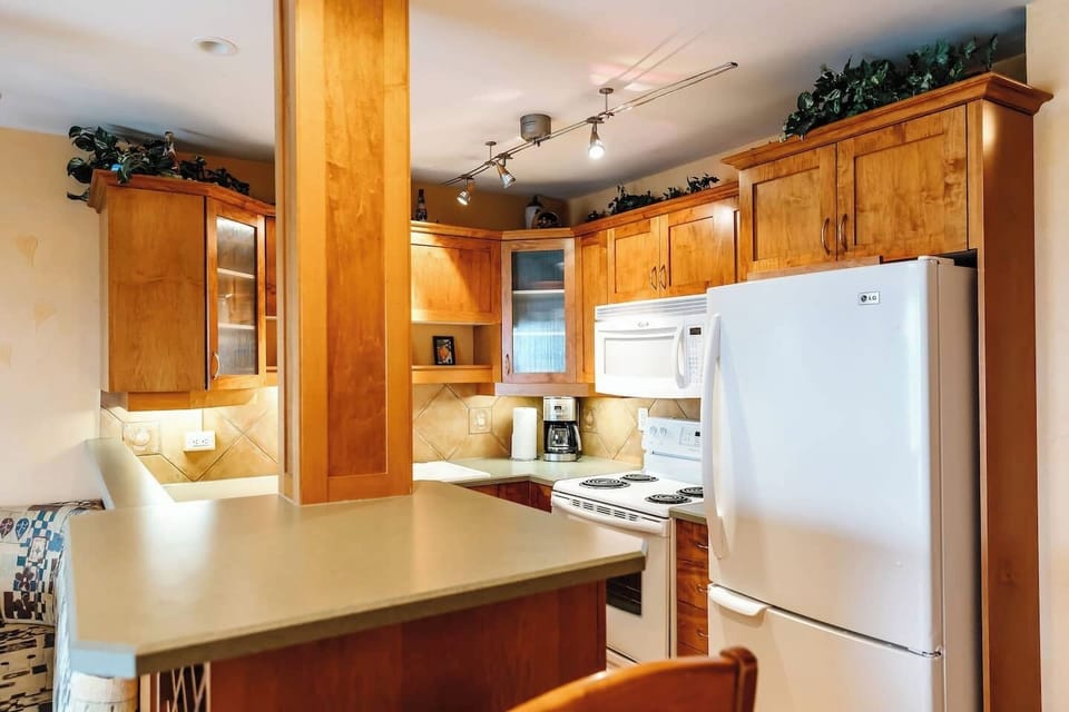 Kitchen with a breakfast bar, two bar stools, and appliances including a stove,and refrigerator