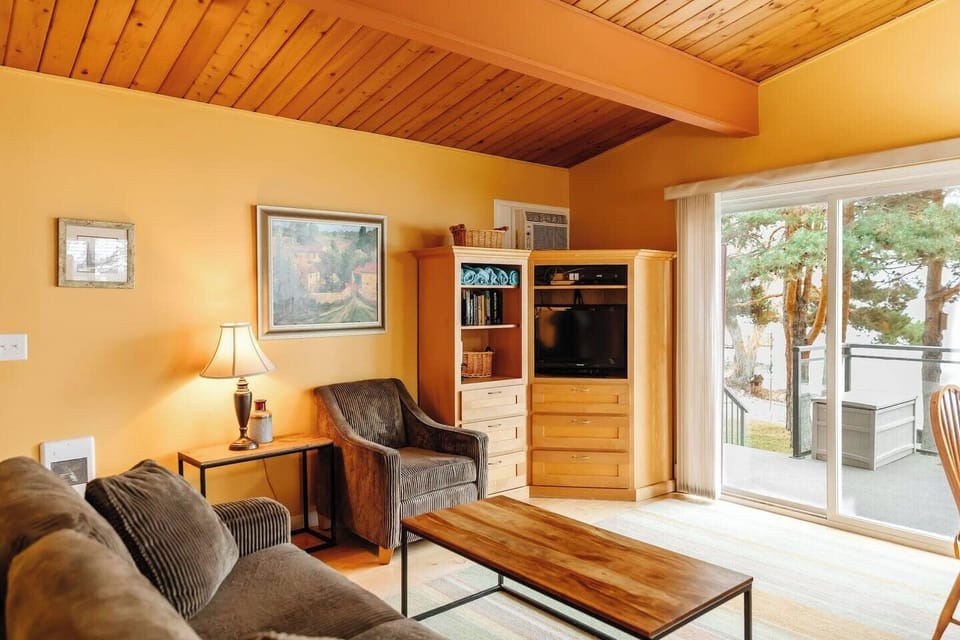 A welcoming living space with a couch, armchair, coffee table, and a door leading outside—perfect for lounging or enjoying fresh air.