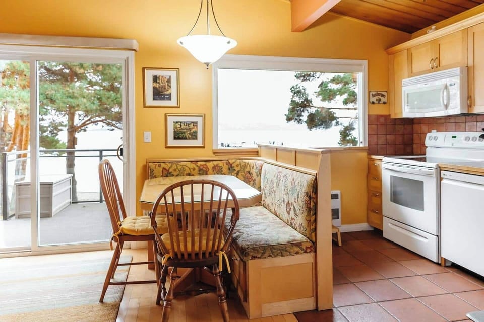 Enjoy meals in the dining area, featuring a table and chairs, while taking in the beautiful outdoor view through the window.