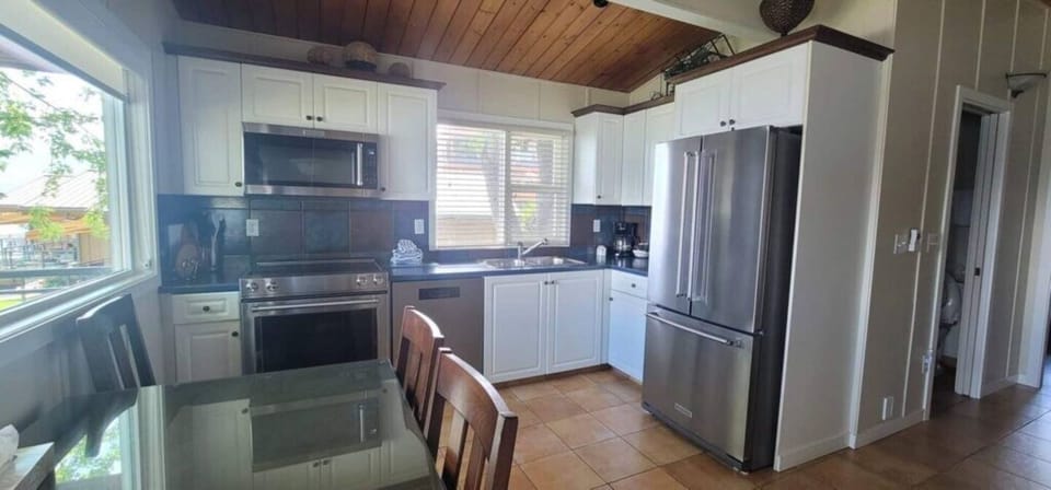 Bright kitchen with white cabinets, stainless steel appliances, and a window for natural light.
