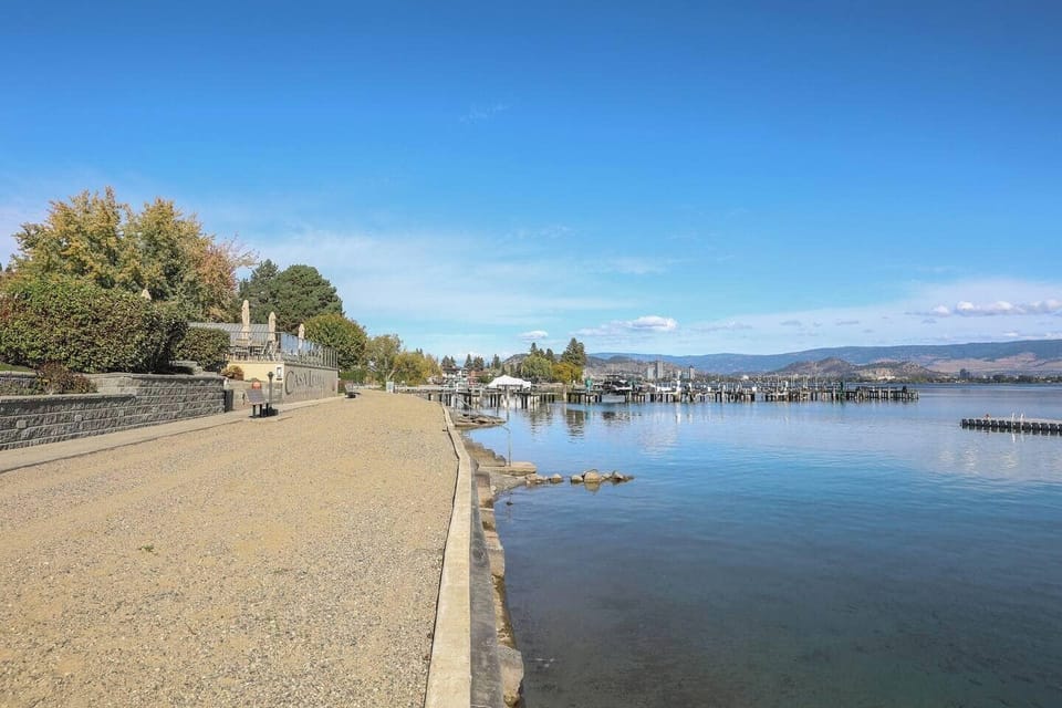 Concrete walkway by the lake, with a marina in the background offering a serene lakeside view.