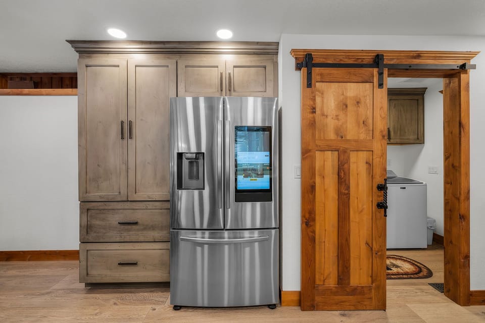 Your modern kitchen features a stainless steel smart refrigerator and rustic barn door that slides to reveal laundry space.