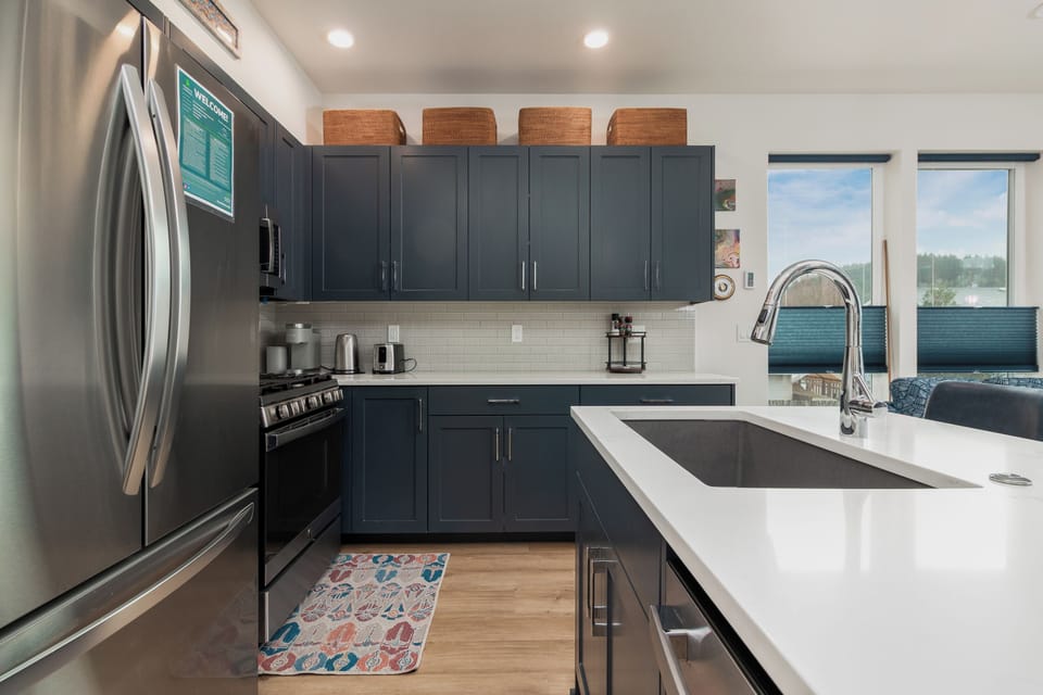 Your modern kitchen features sleek navy cabinetry, stainless steel appliances, and pristine quartz countertops perfect for preparing memorable meals.