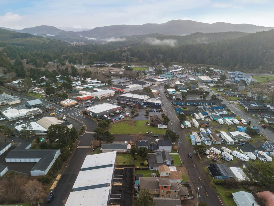 Aerial view of charming coastal town nestled between forested mountains and valley, showcasing local community character.