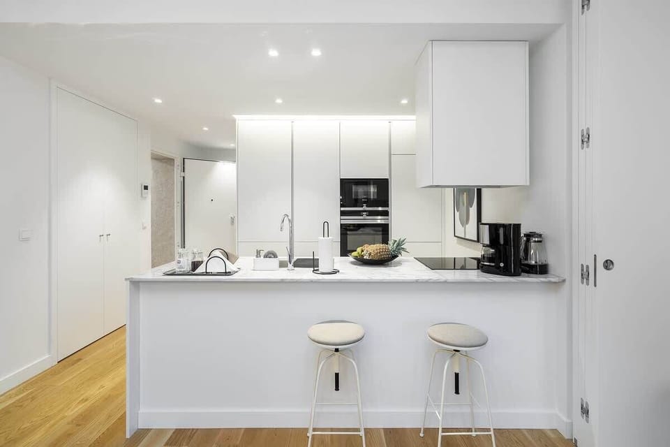 Open-plan kitchen with white cabinetry, a large island with bar stools, and stainless steel appliances. Perfect for cooking and entertaining, with plenty of counter space and natural light.
