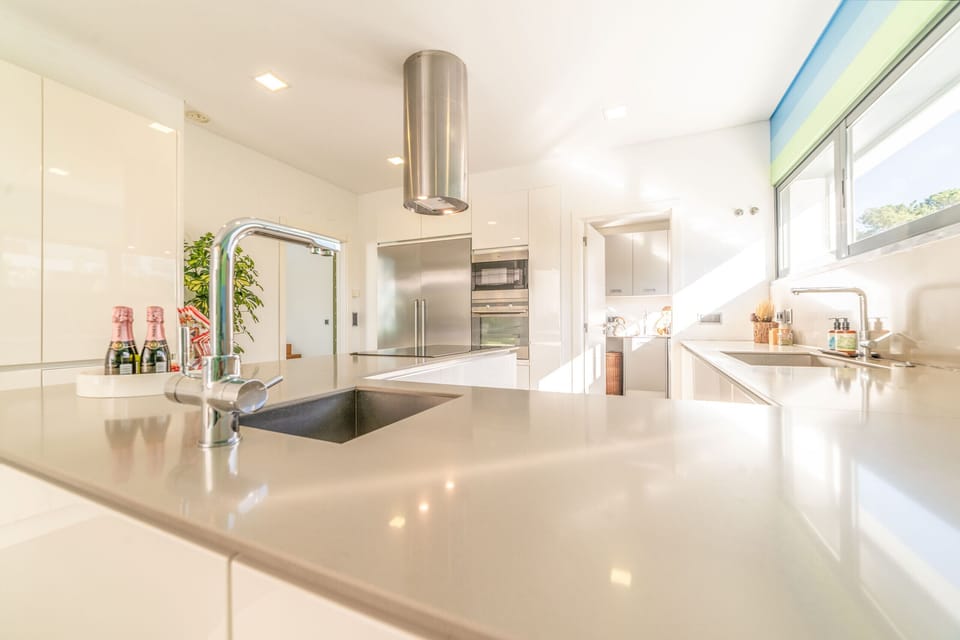 Modern white kitchen with island and stainless steel appliances — Villa Maria, holiday villa in Herdade de Aroeira