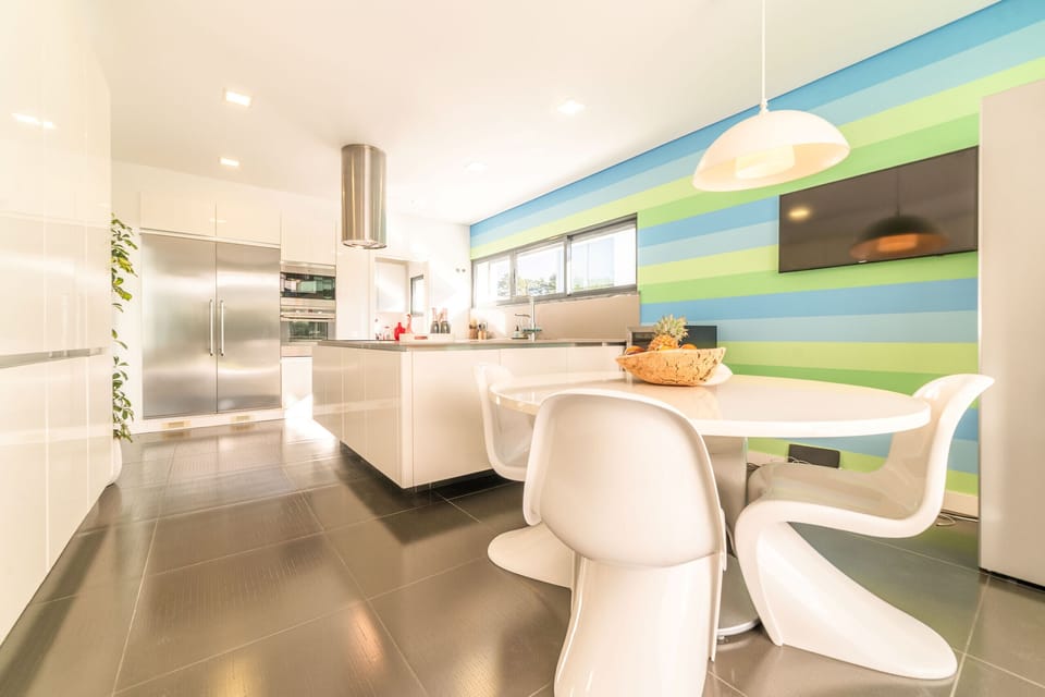 Modern open-plan kitchen with colourful striped accent wall — Villa Maria, holiday villa in Herdade de Aroeira
