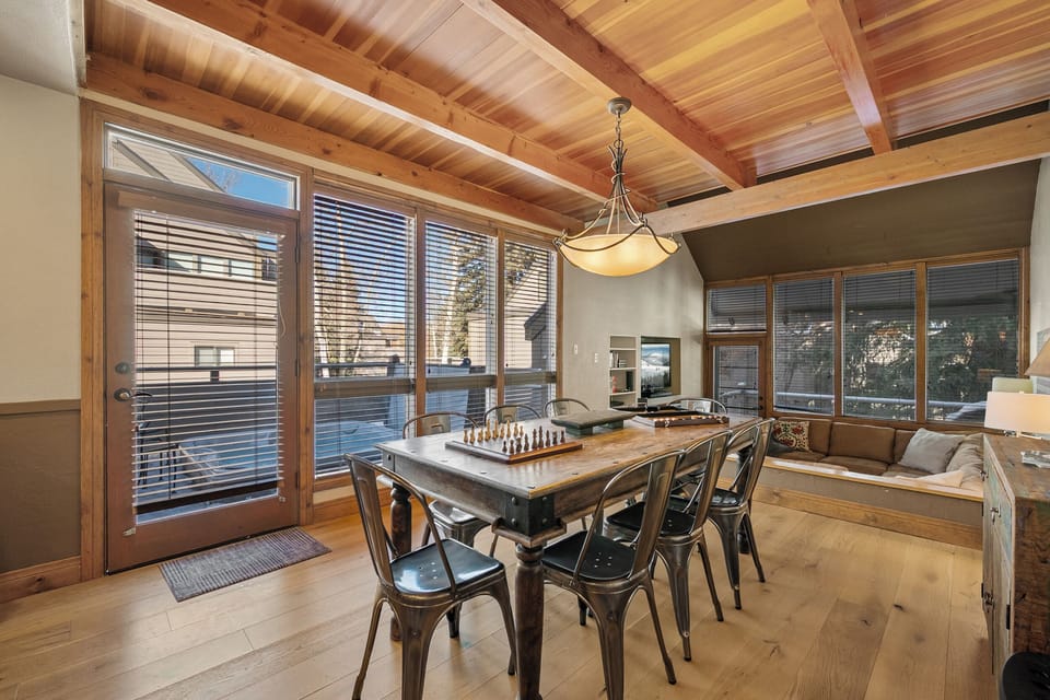 Gather around this beautiful dining table under soaring wood beam ceilings, where you'll enjoy meals surrounded by floor-to-ceiling windows.