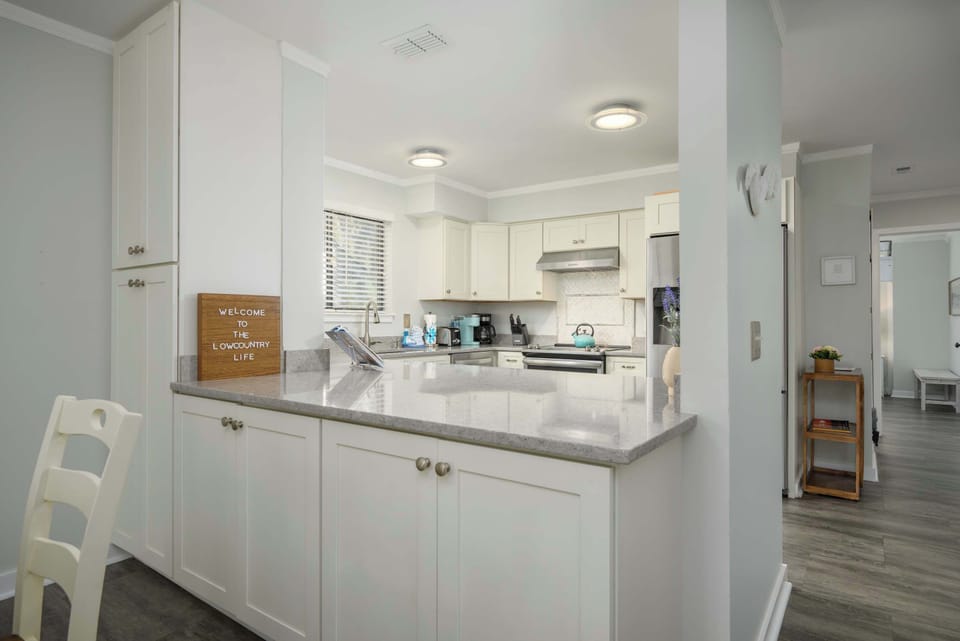 Modern kitchen with white shaker cabinets, gray countertops, and stainless steel appliances.