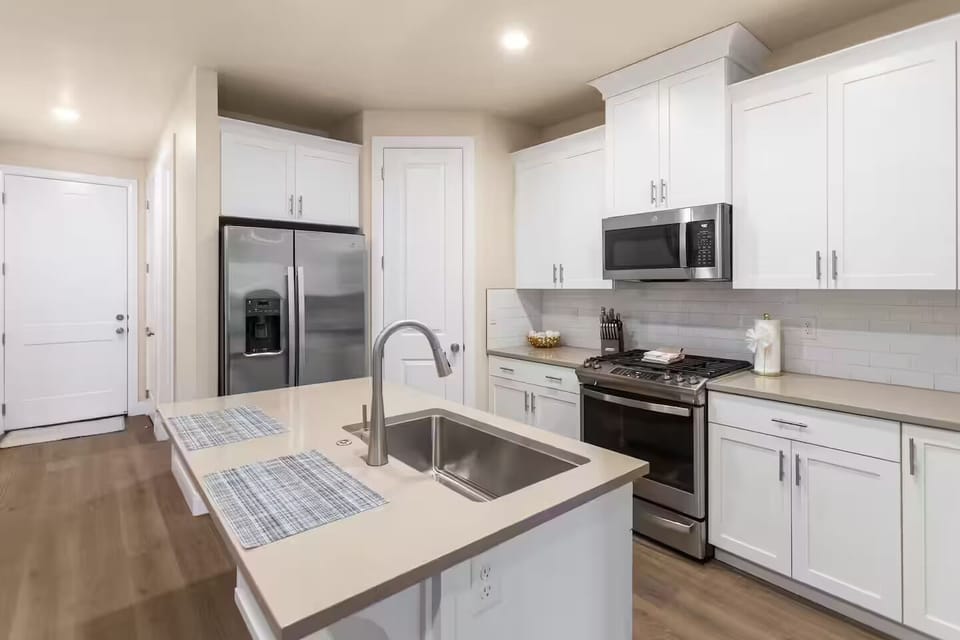 Fully stocked kitchen with stainless steel appliances and thick solid-surface countertops connecting the dining area and living room.
