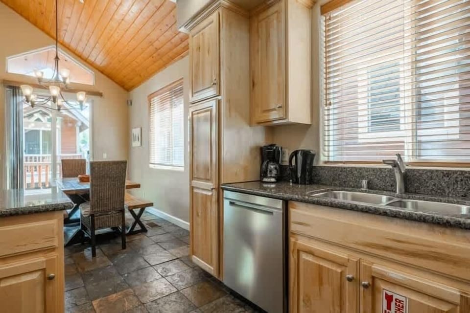 Modern kitchen with stone counters, stainless appliances, and warm wood cabinetry.