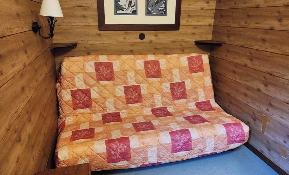 The traditional fold-out sofa bed adds a touch of comfort and nostalgia, inviting guests to relax in this alpine-inspired nook.