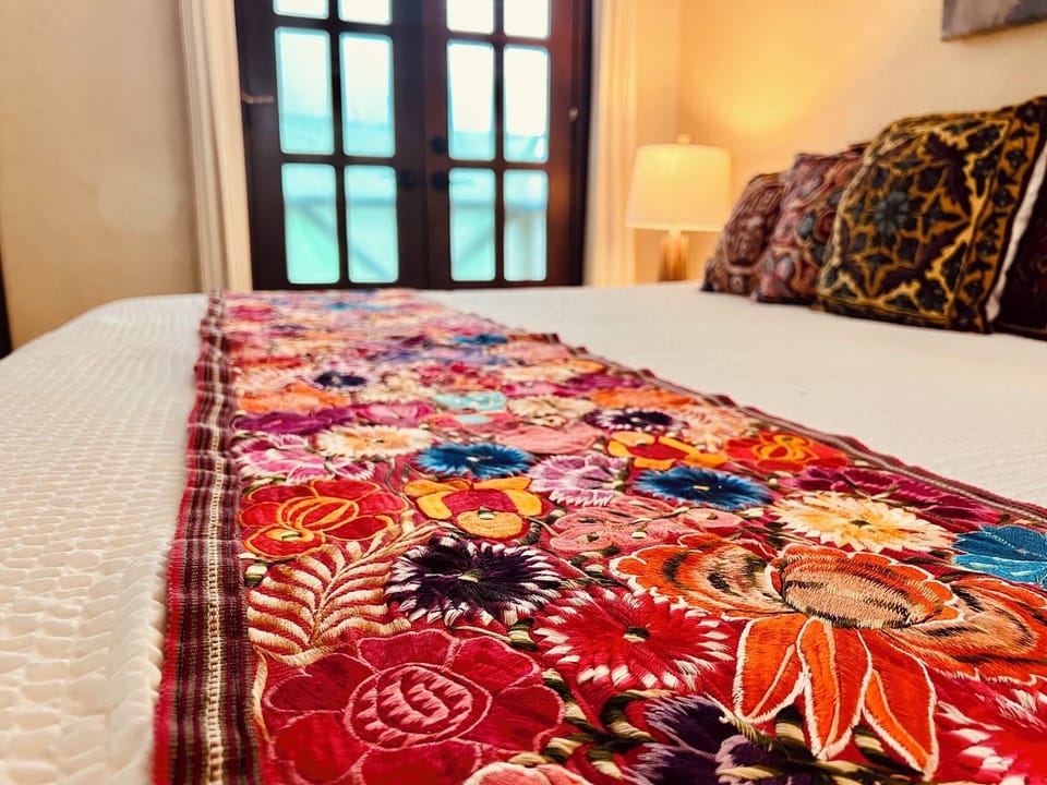 Luxury suite bed featuring an authentic, vibrant hand-woven textile runner.
