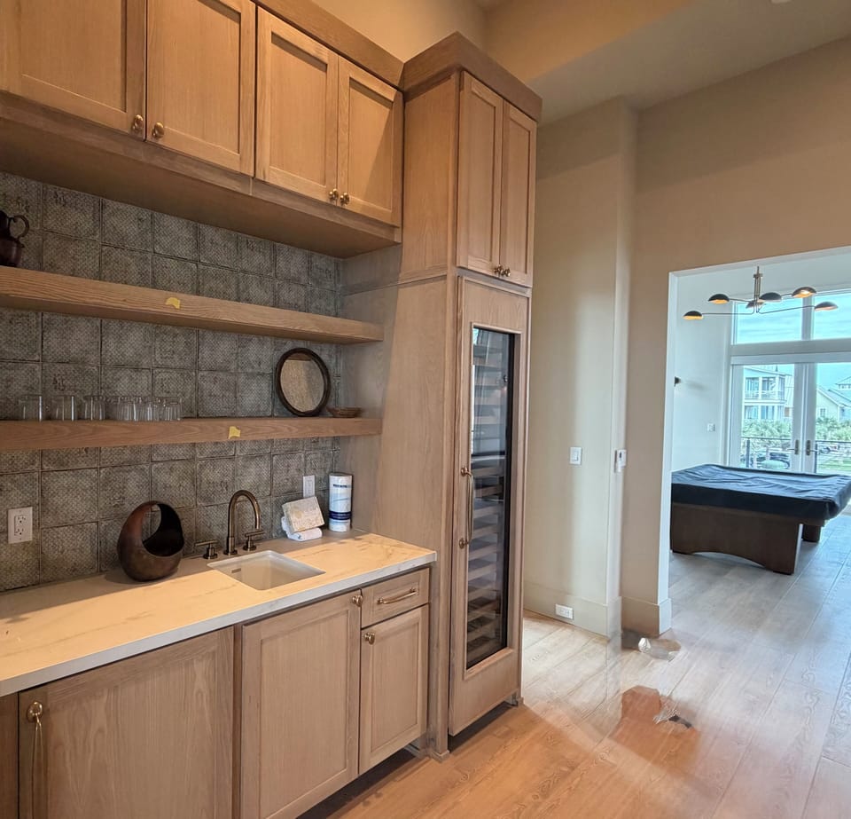 The level 2 bar is between the main living area and game room with a full size Sub Zero wine fridge