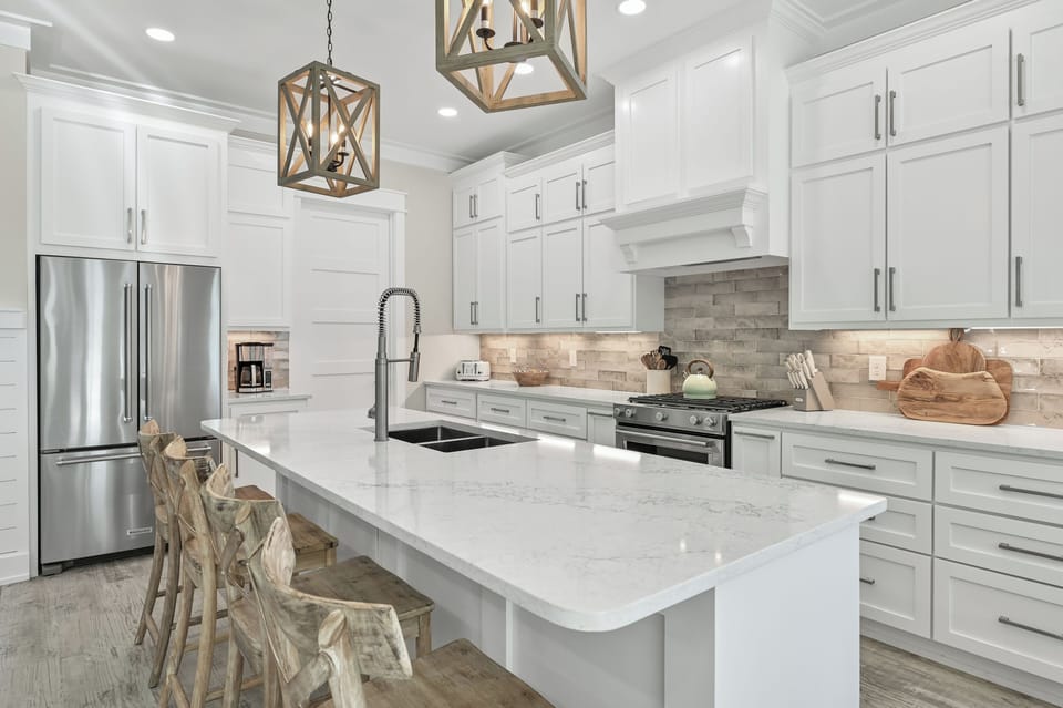 Chef’s kitchen featuring white cabinetry, a large island, and subway tile backsplash.